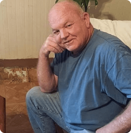 Man sitting and smiling in casual clothes.