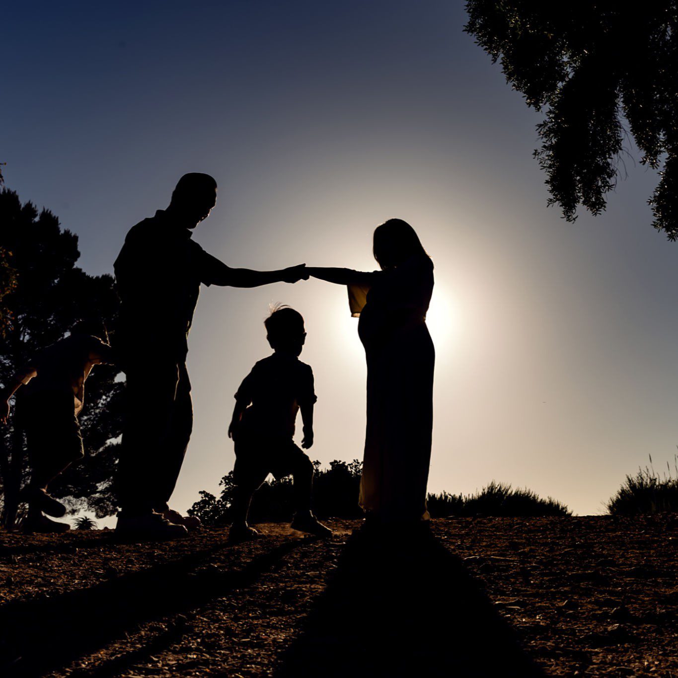 Silhouetted family holding hands at sunset.