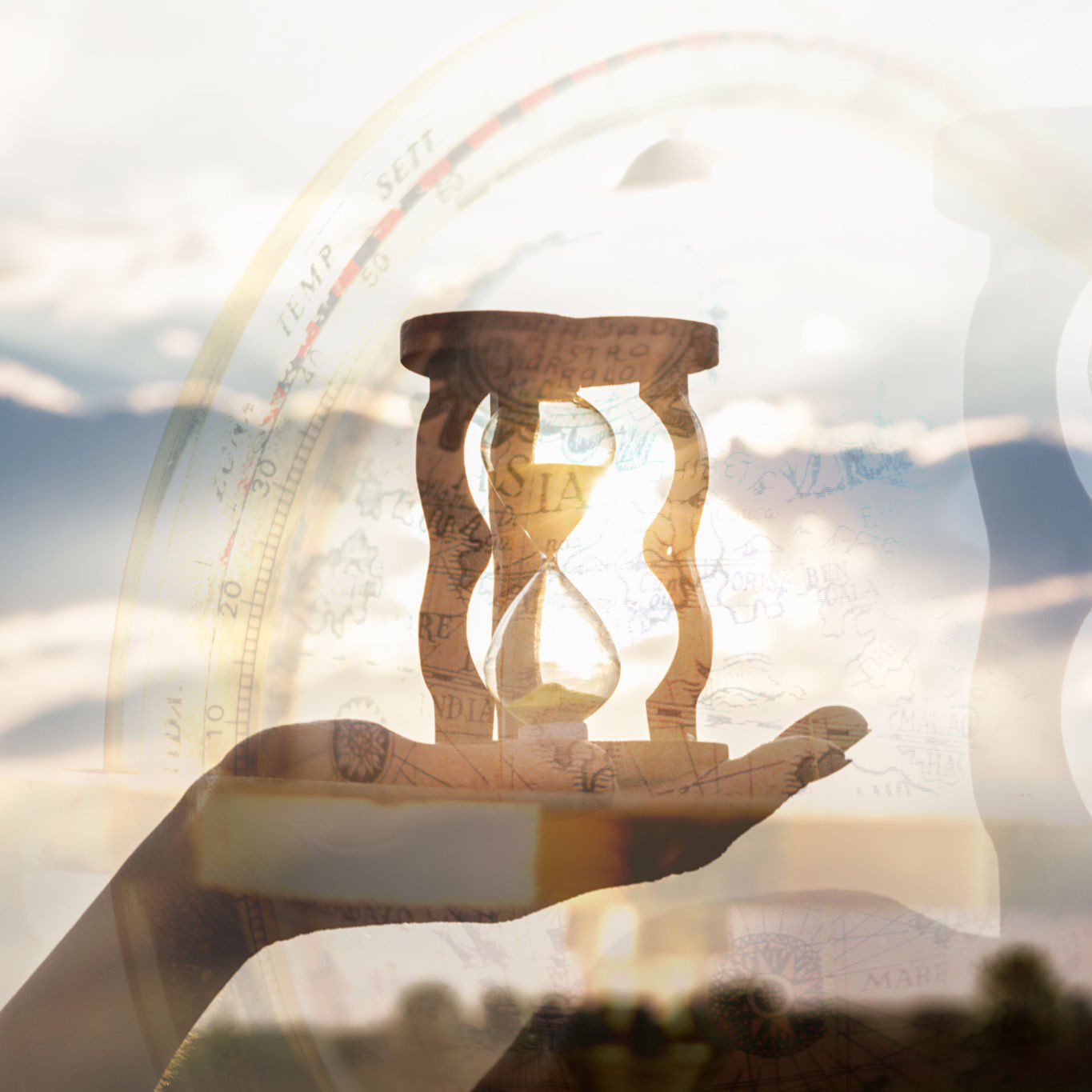 Hand holding hourglass against cloudy sky.